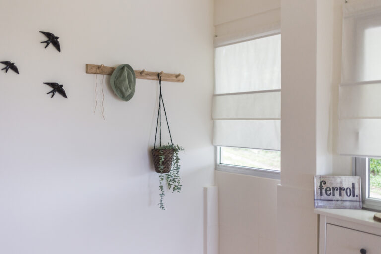 Perchero decorativo junto a una ventana con estores