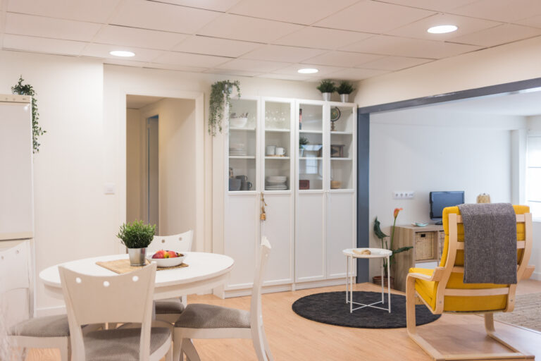 Comedor y salón en zona diáfana con vitrina y sillón amarillo