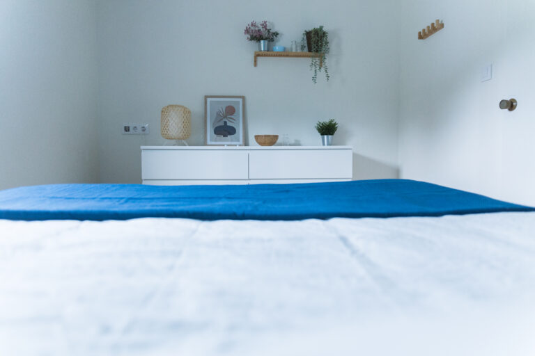 Dormitorio con cómoda blanca, cuadros y ropa de cama azul