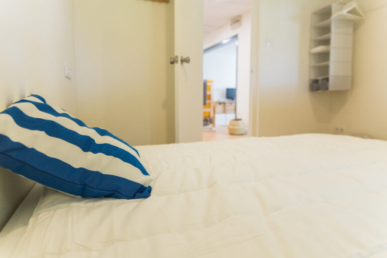 Detalle de cojín a rayas azules sobre la cama