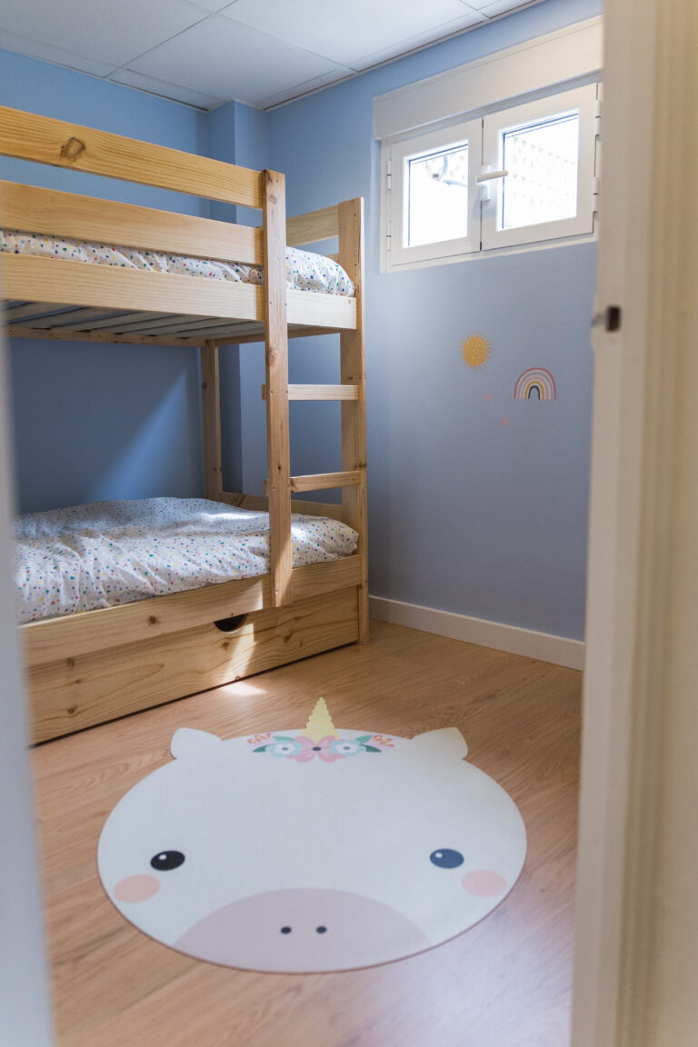Habitación infantil con litera de madera y alfombra con forma de animal